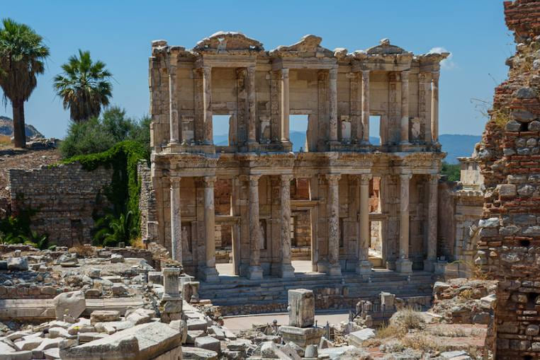 Fachada de mármol de dos pisos de la Biblioteca de Celso en Éfeso, alzándose sobre un campo de bloques de piedra caídos
