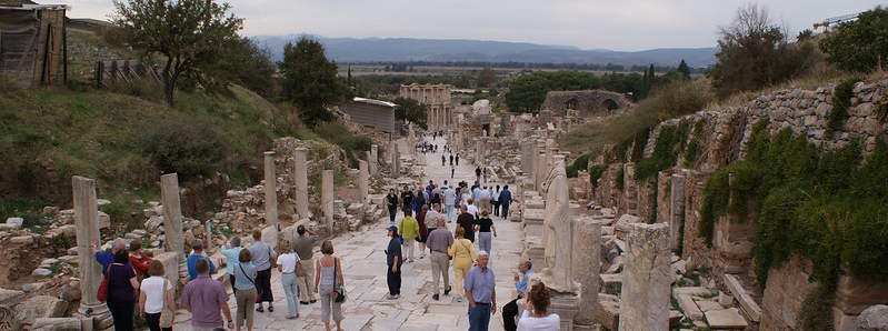 Grupo de turistas caminando por la Calle de los Curetes en Éfeso bajo el sol de verano