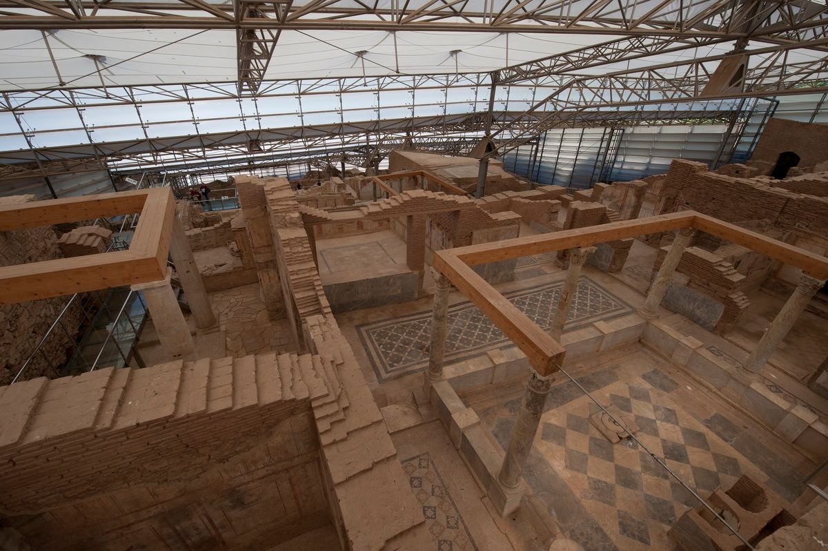 Suelos de mosaico geométrico, columnas y muros de ladrillo de las Casas Terraza de Éfeso bajo la gran cubierta de estructura metálica