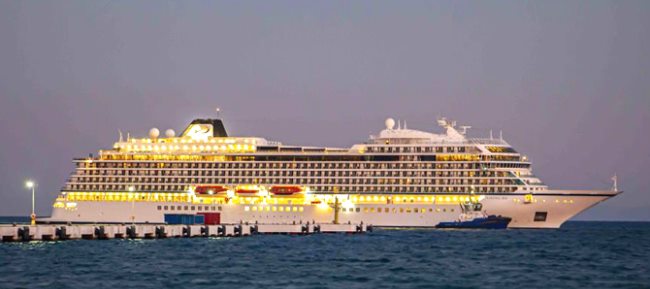 Un crucero iluminado al atardecer atracado en el puerto de Kuşadası