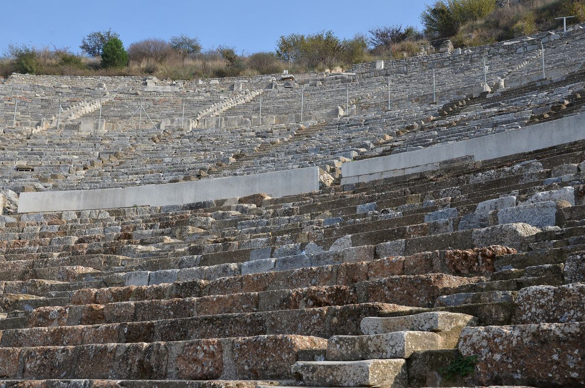 Gradas de piedra del Gran Teatro de Éfeso vistas desde abajo, subiendo en filas hasta la parte alta de la colina bajo un cielo azul