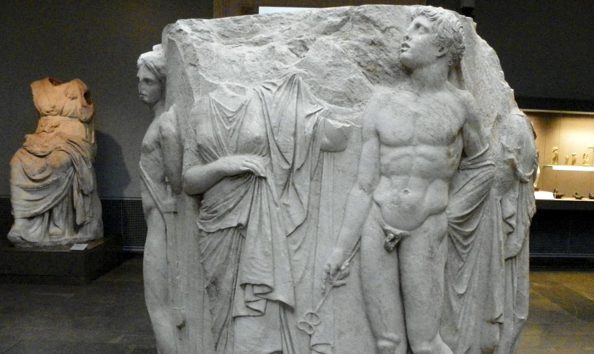Tambor de columna de mármol del Templo de Artemisa esculpido con figuras en relieve, entre ellas un joven desnudo con un caduceo, expuesto en una sala del British Museum