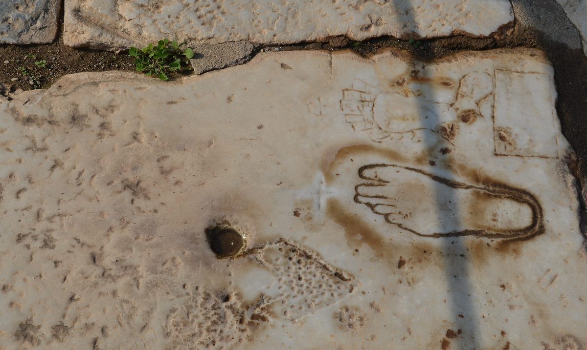 Grabados antiguos en una losa de mármol de Éfeso: la silueta de un pie, una figura femenina y un panel rectangular