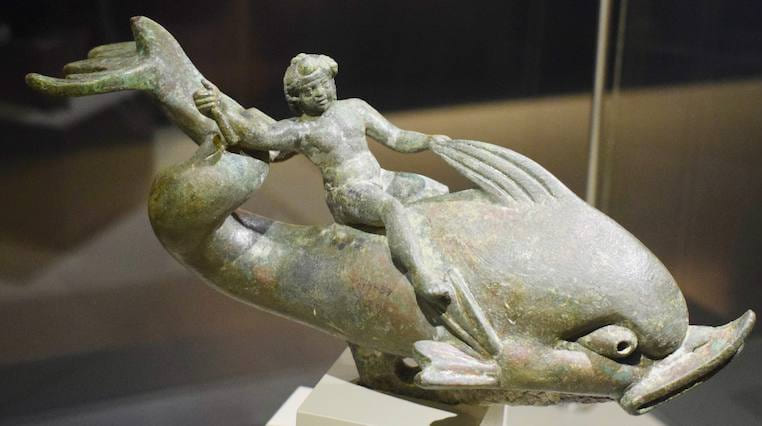 Estatuilla de bronce de Eros cabalgando un delfín, expuesta en una vitrina del Museo de Éfeso
